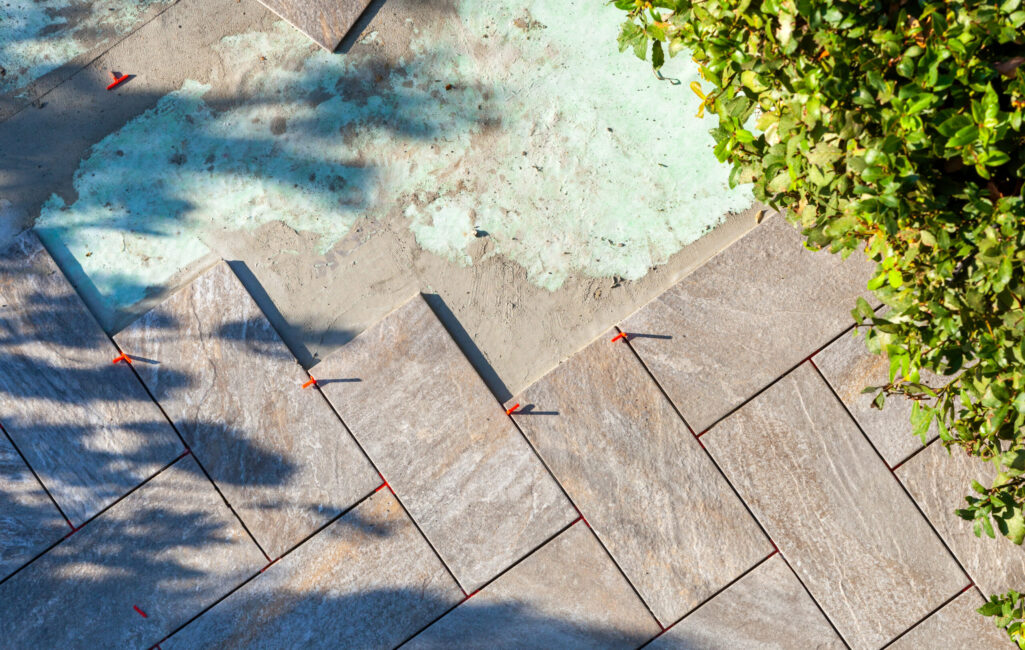 Laying outdoor flooring with the use of red spacers for the joints.